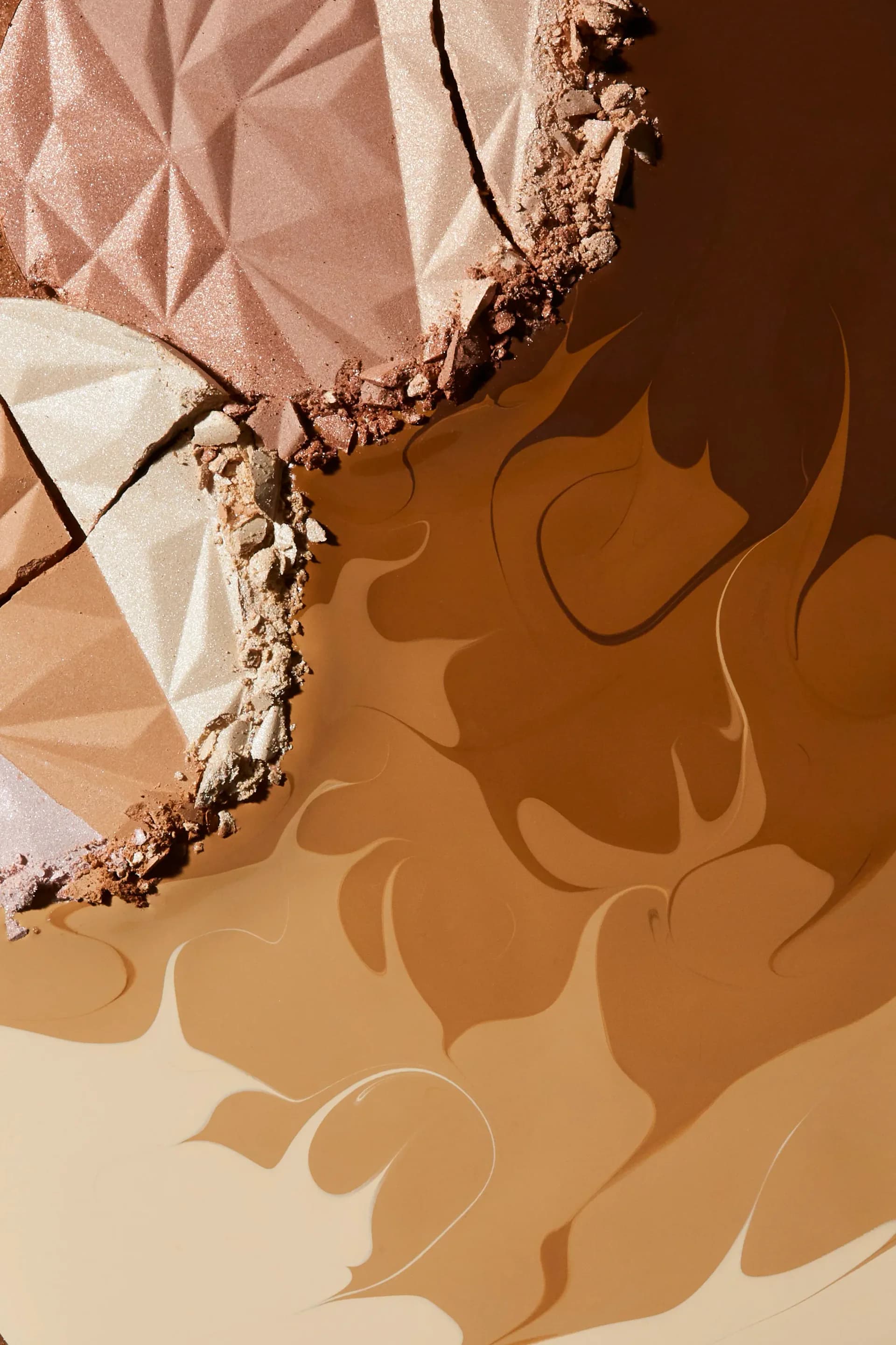 Close-up macro shot of cracked powder compacts showing pink and gold shimmer textures on brown background