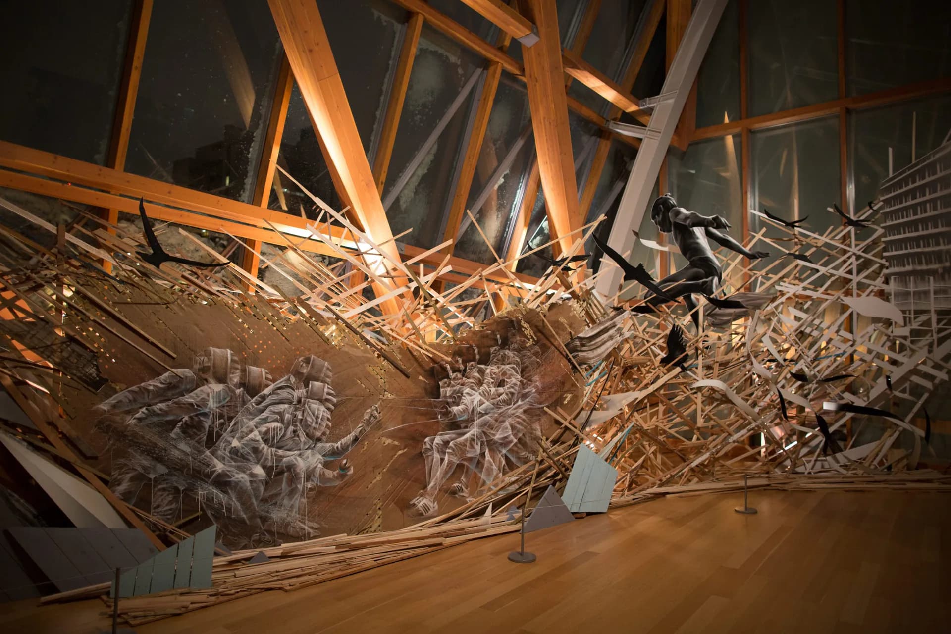 Large-scale installation with painted figures on wooden debris structure with galloping horses