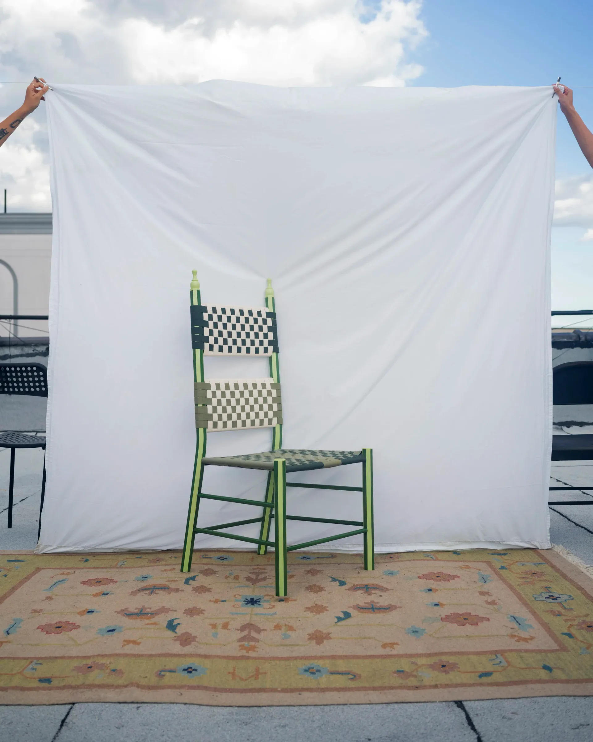 Single green checkerboard woven chair against white backdrop