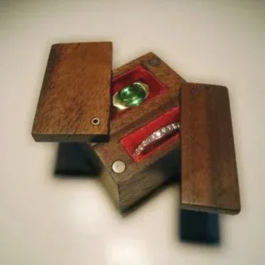 Open wooden ring box with velvet interior holding a gemstone and diamond ring