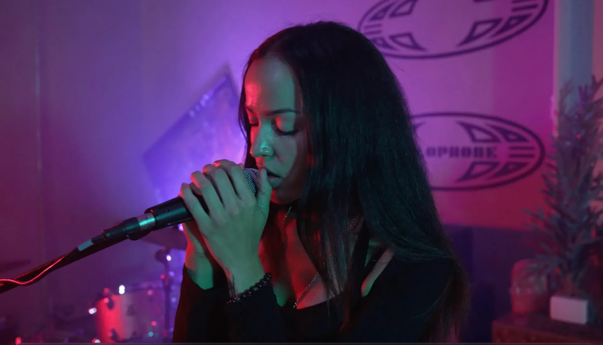 Singer performing with microphone under dramatic purple and red stage lighting