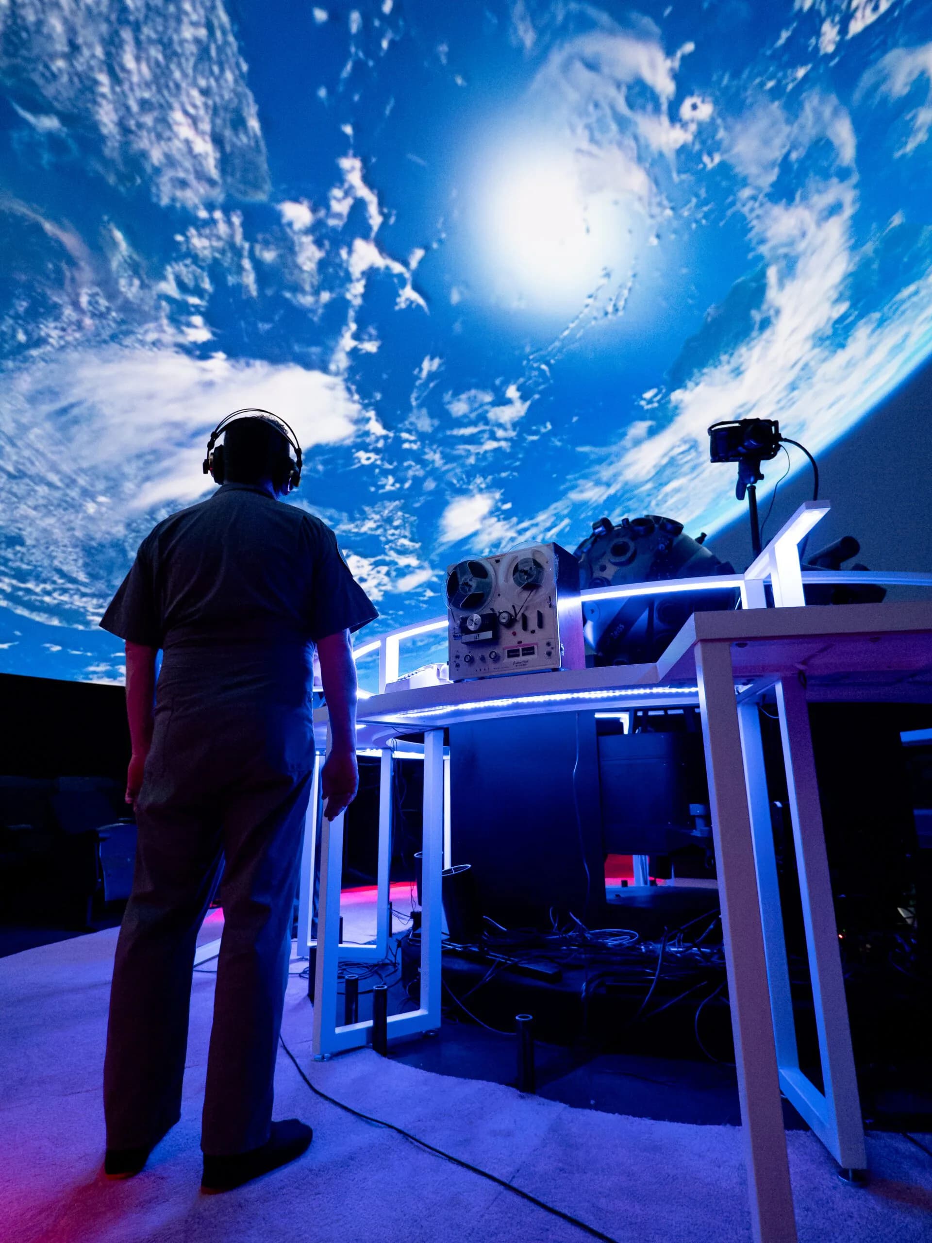 Performer singing into microphone beneath a dome projection of Earth from space