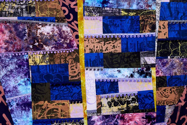 Mixed-media collage with patchwork squares in vibrant blues, purples, pinks, and golds featuring distressed textures and decorative patterns.