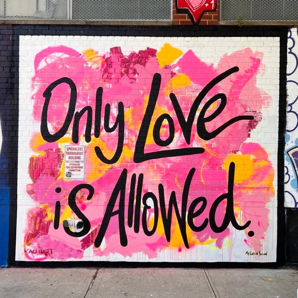 Only Love is Allowed mural in pink and yellow on brick wall
