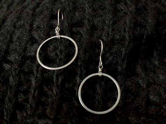 Single silver hoop earrings on dark knit fabric