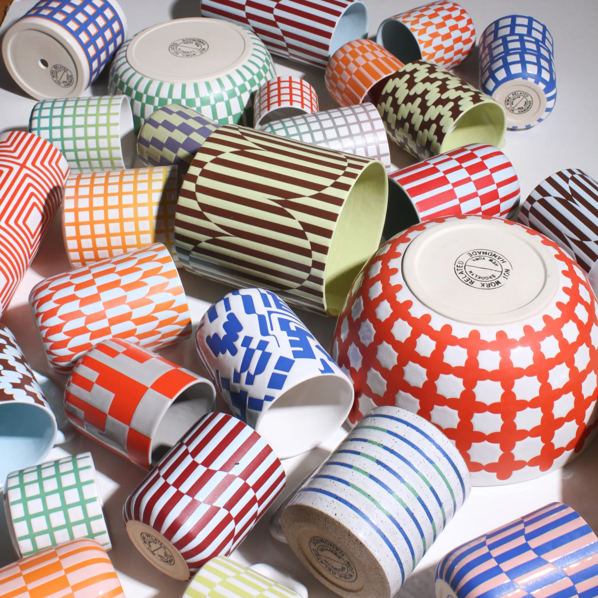 Collection of colorful geometric patterned ceramic cups and bowls scattered together