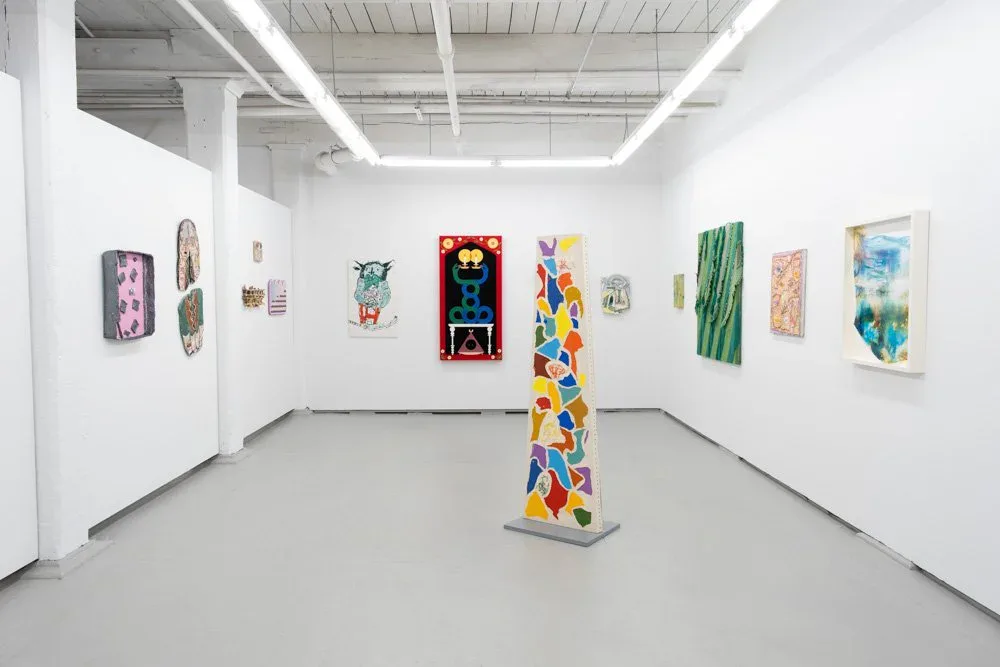 Gallery installation with colorful mural painting and sculptural elements including mint-green relief works and a staircase