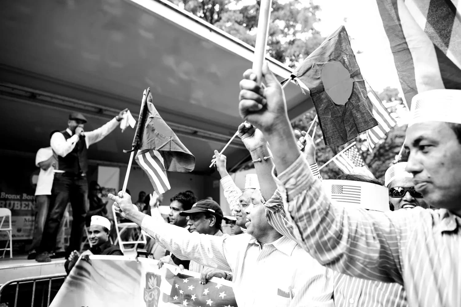Black and white photograph of a crowd holding American flags at an outdoor public gathering or demonstration.