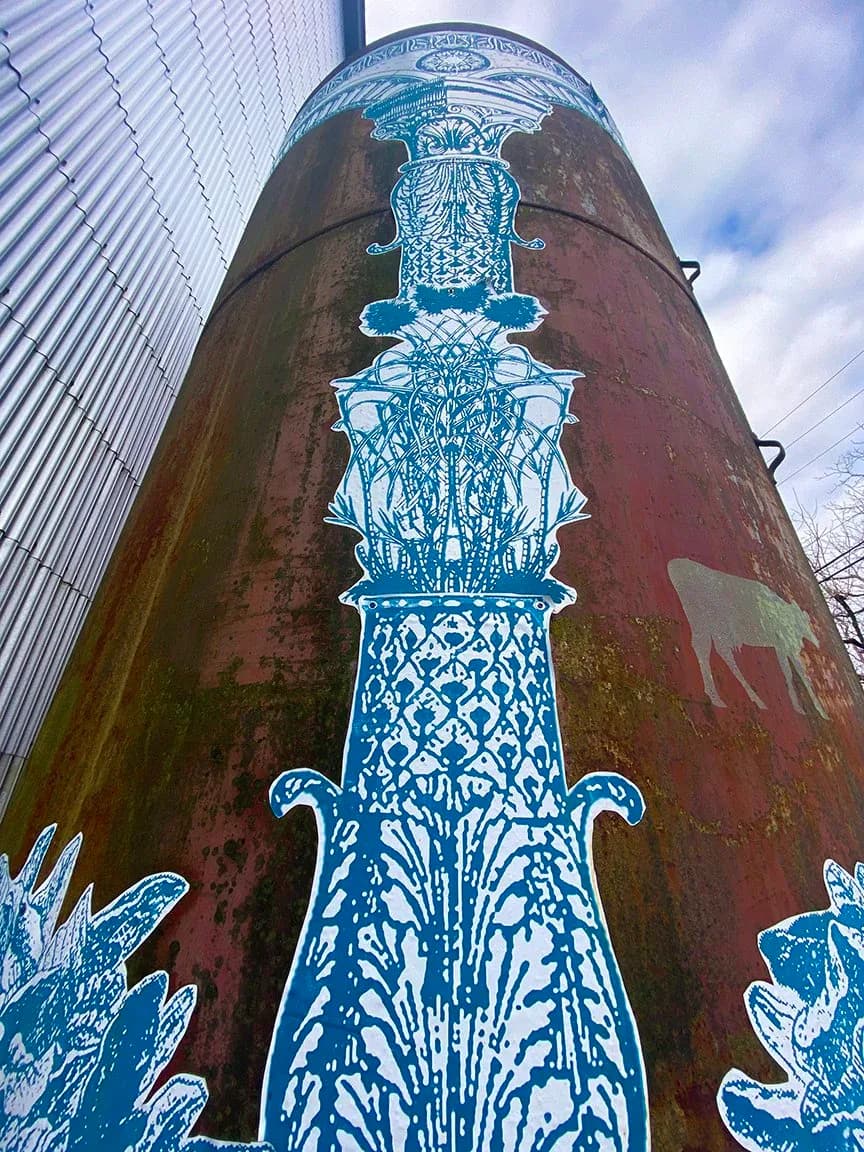 Ornate blue and white porcelain-style painted column or tower structure on weathered red cylindrical surface, inspired by chinoiserie design.