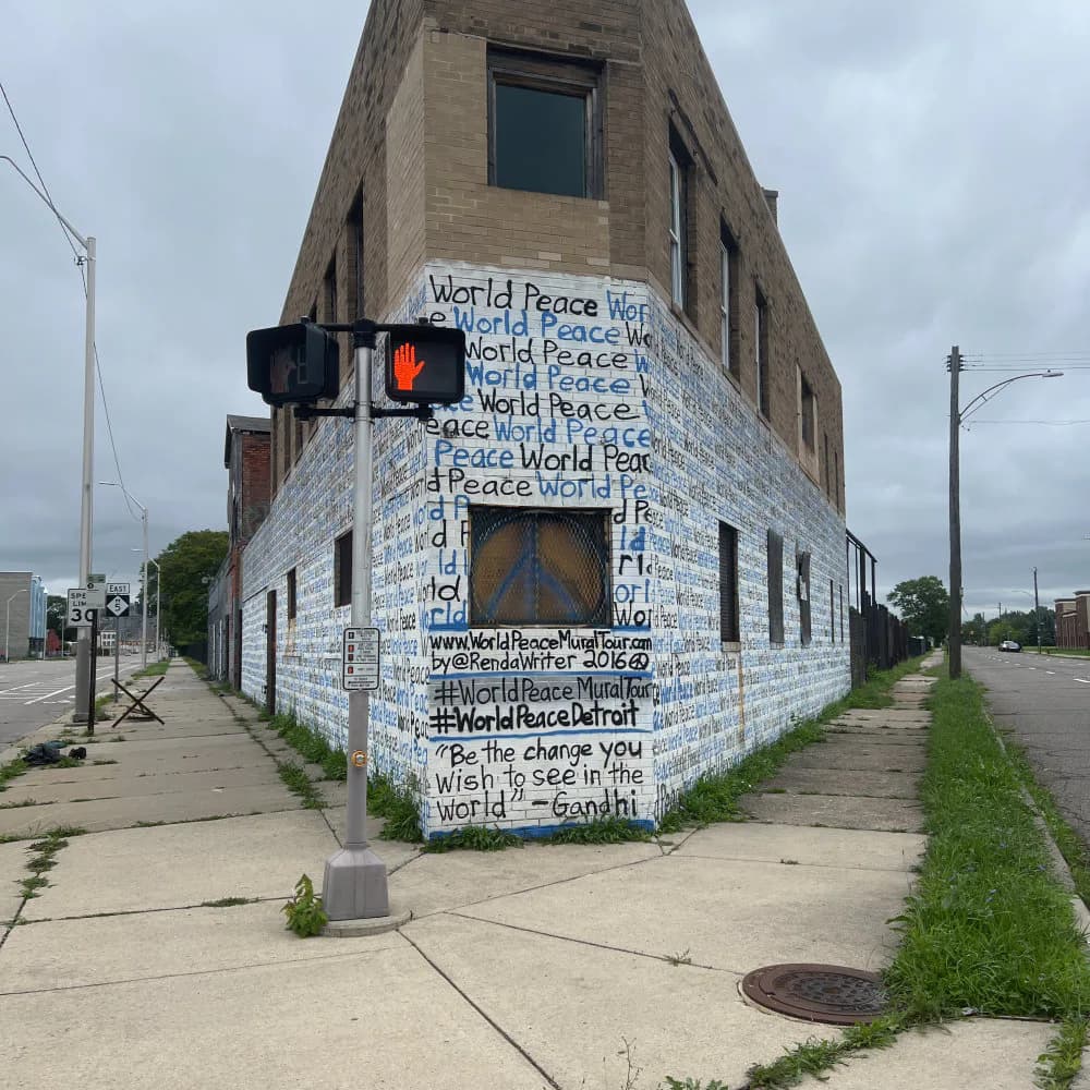 Corner building mural in white with blue and black text reading "World Peace" and additional handwritten-style text, covering the angled facade.