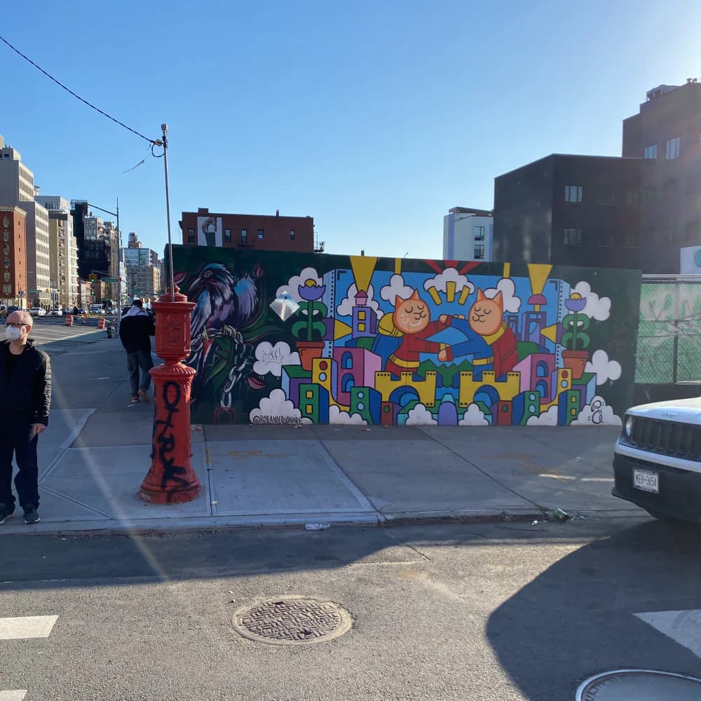 Vibrant street mural by Rob Anderson featuring colorful geometric shapes, playful characters, and bold typography on an urban wall.