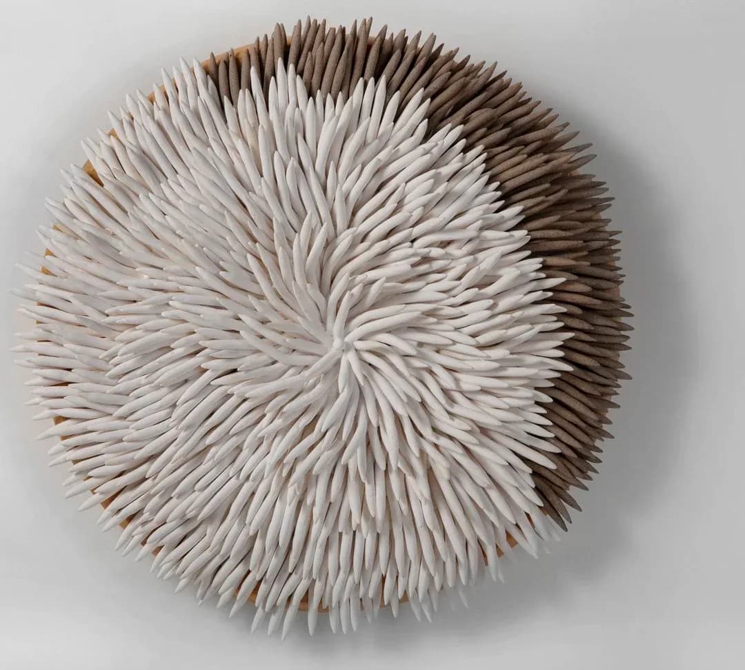 Circular wall sculpture with white and brown ceramic spines radiating from center