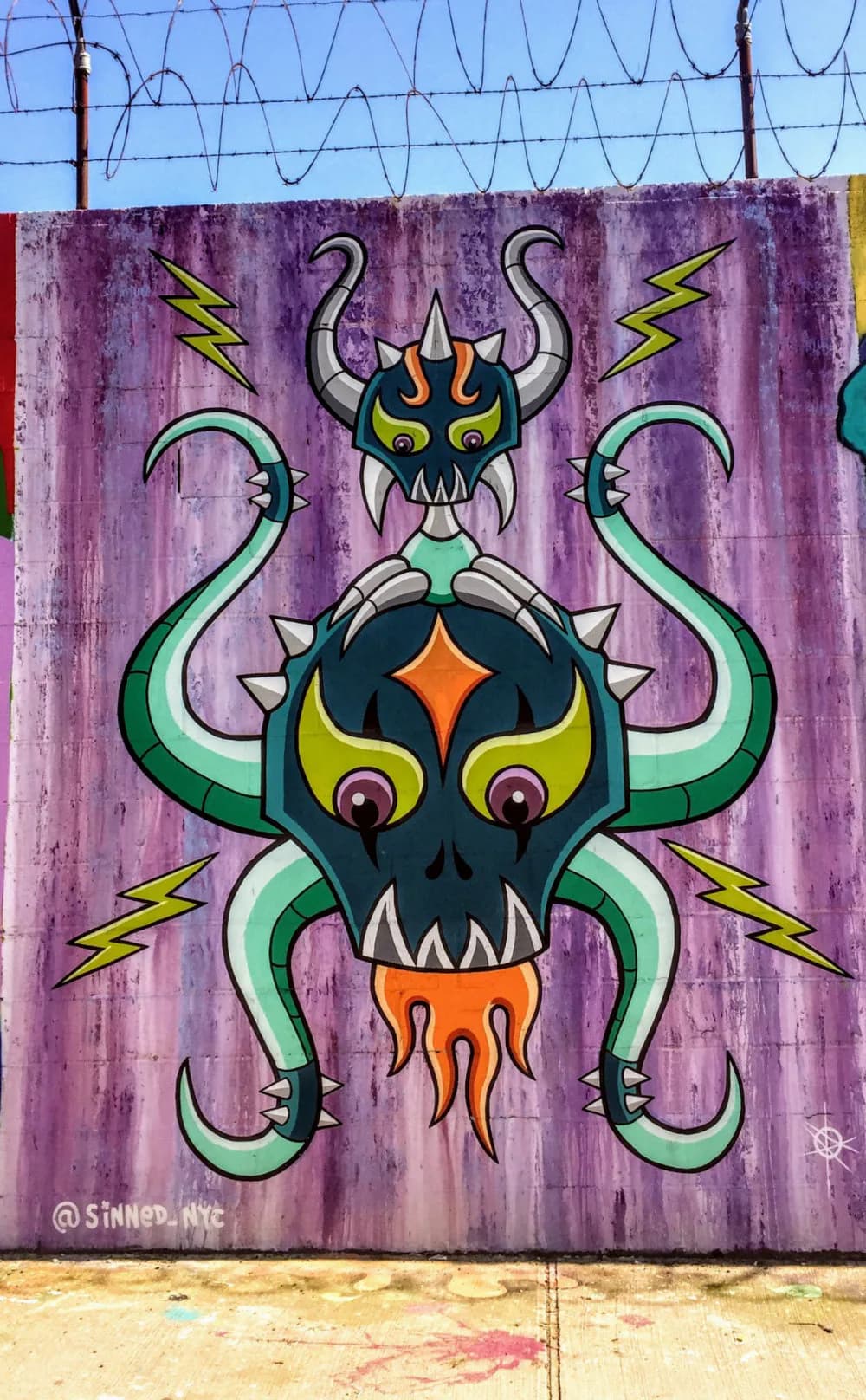 Sinned's mural on lavender background: stylized demon face with horns, glowing yellow eyes, orange mouth, green tentacles, and yellow lightning bolts.
