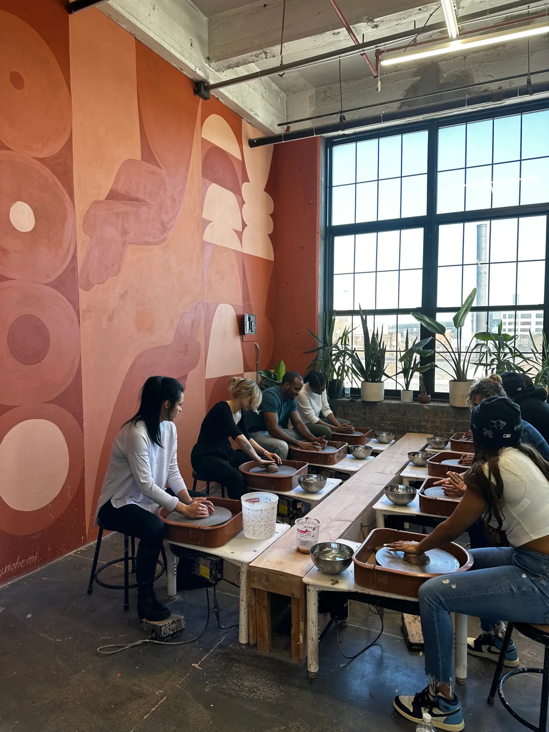 Large-scale abstract mural with terracotta and blush tones featuring geometric organic forms in a studio space