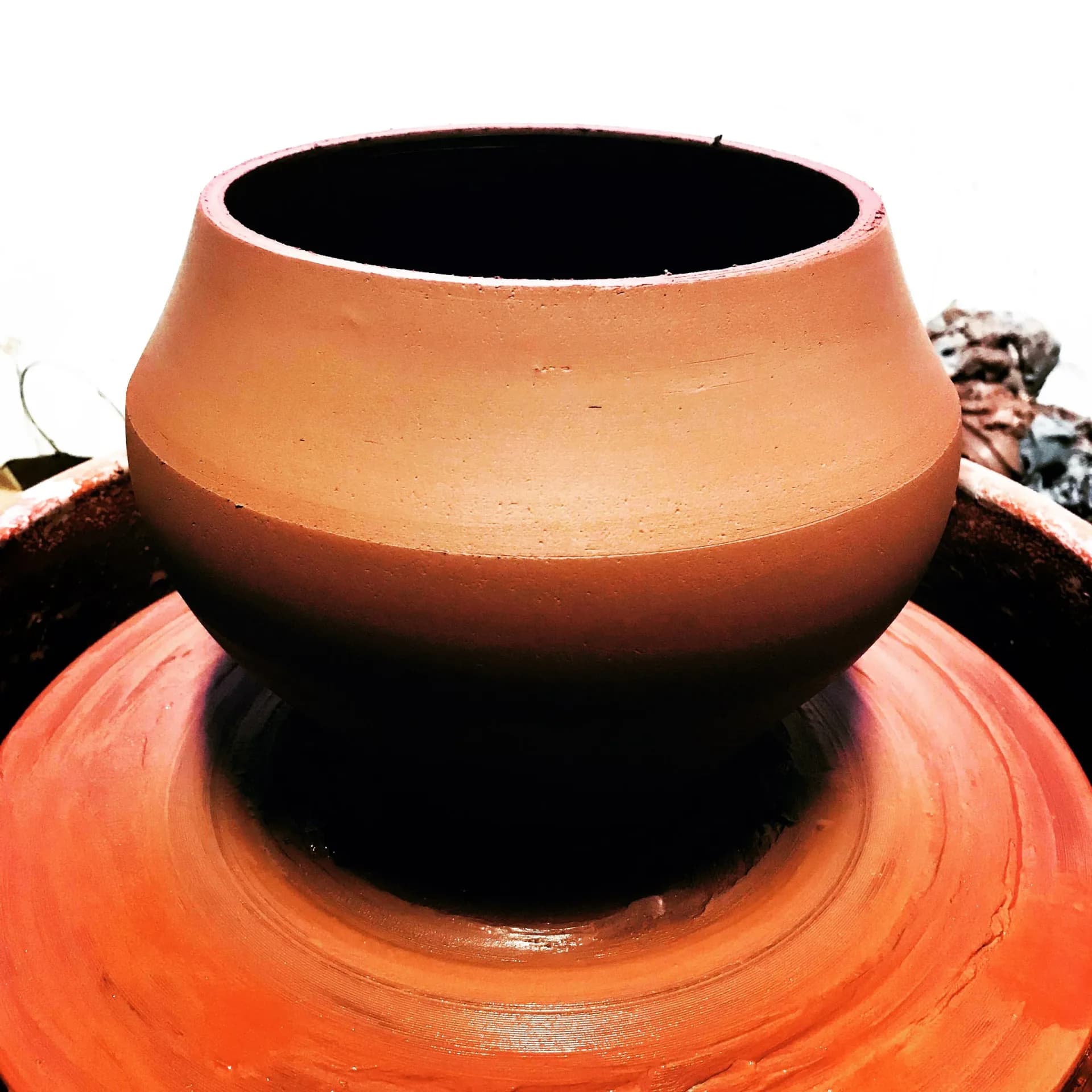Freshly thrown terracotta ceramic jar on the pottery wheel with clean sculptural form