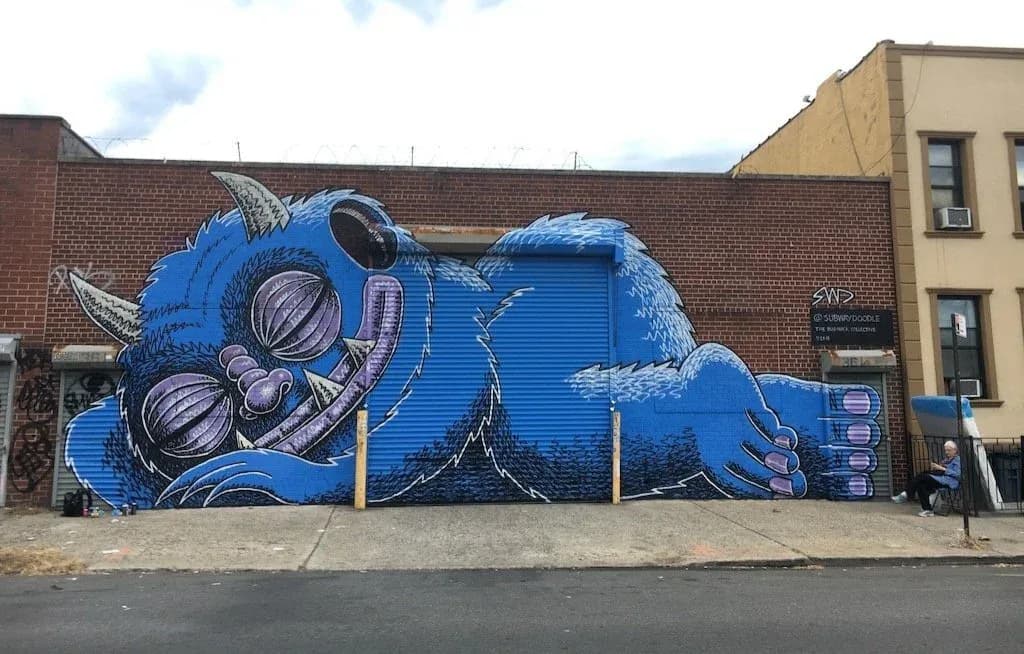 Large blue monster mural sleeping across entire building facade in Bushwick Brooklyn