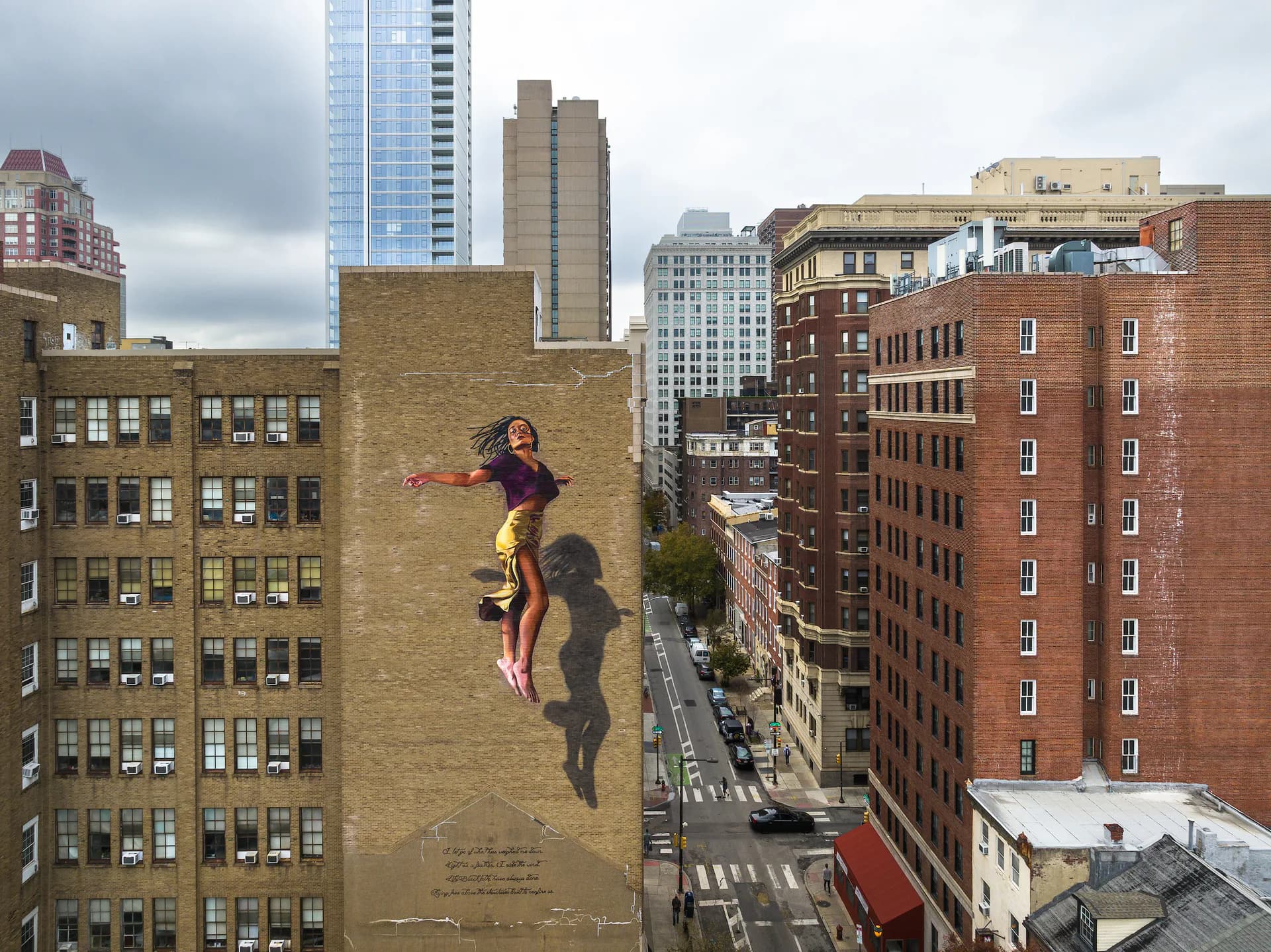 Large-scale mural of a leaping woman on a city building facade in Philadelphia
