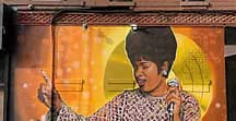 Large-scale mural of a woman singing into a microphone with golden circular background