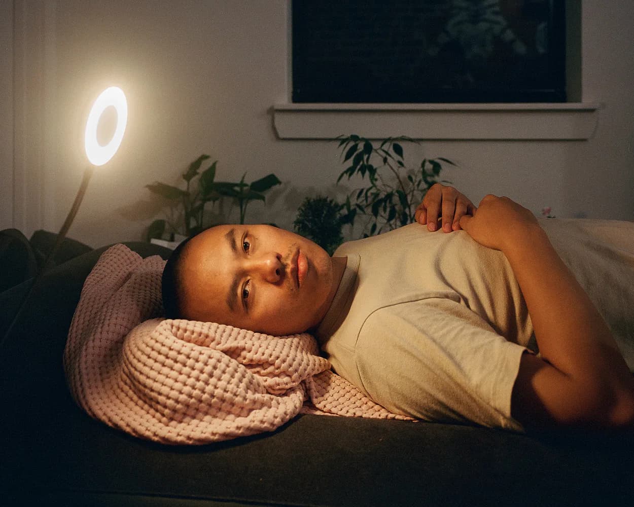 Two figures embracing outdoors under a large tree in dappled sunlight