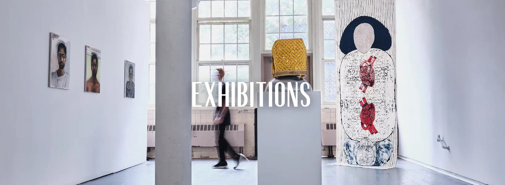 Bright gallery interior with white walls, large windows, and the word EXHIBITIONS in white text; a sculptural figure and abstract artwork visible.