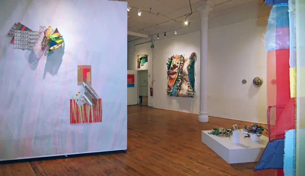 Gallery interior at Abrazo Interno Gallery @ The Clemente showcasing colorful mixed-media works on walls and pedestals, with bold geometric and abstract compositions.