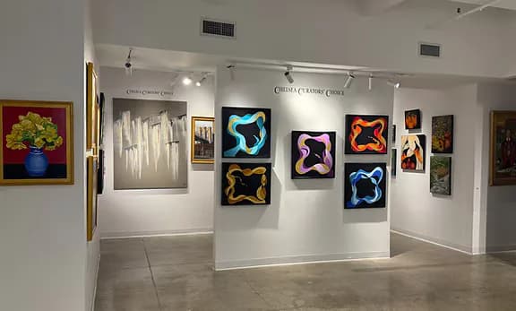 Chelsea gallery interior with white walls and polished concrete floor displaying neon animal outline artworks in bright colors (pink, blue, orange) alongside framed paintings and photographs.