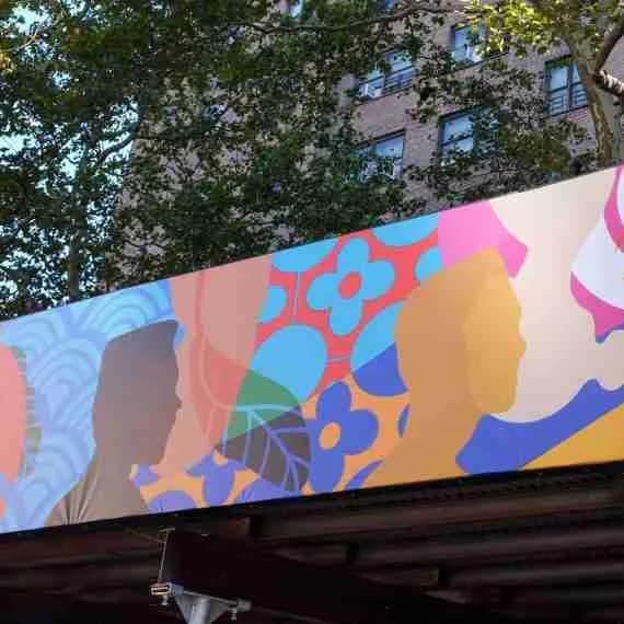 Colorful mural featuring abstract silhouettes of faces in profile with geometric patterns in red, blue, yellow, and pink against a light background.