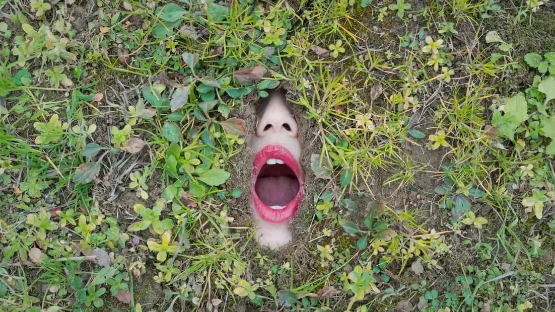 Surreal mixed-media artwork depicting a face with open mouth emerging from green foliage and vegetation.