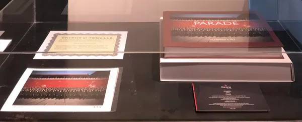 Gallery display at Atelier VGI showing framed photographs and printed materials on a dark wall surface.