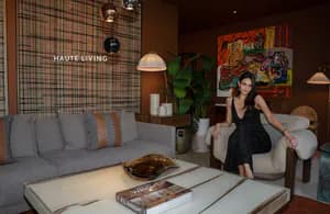 Avant Gallery interior with woman posing near modern furniture, vibrant abstract artwork on brick wall, and minimalist décor.