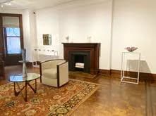 Interior view of Barbara Mathes Gallery featuring fireplace, seating, and patterned floor with open doorway.