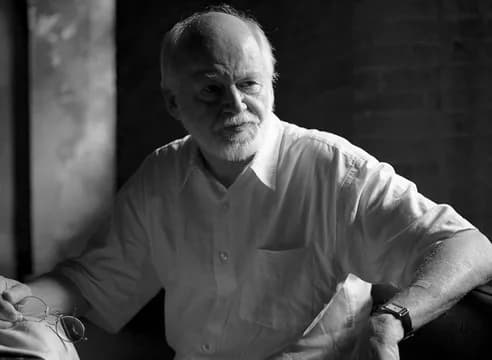 Black and white portrait photograph of an older man with white hair and beard wearing a light-colored shirt.