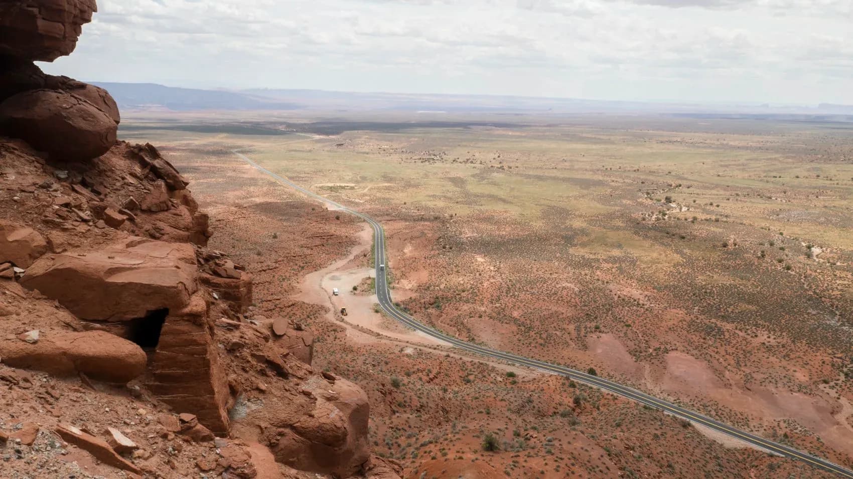 Aerial photograph from a rocky outcrop showing a winding river through arid, desert landscape with scattered settlements and mountains in distance.