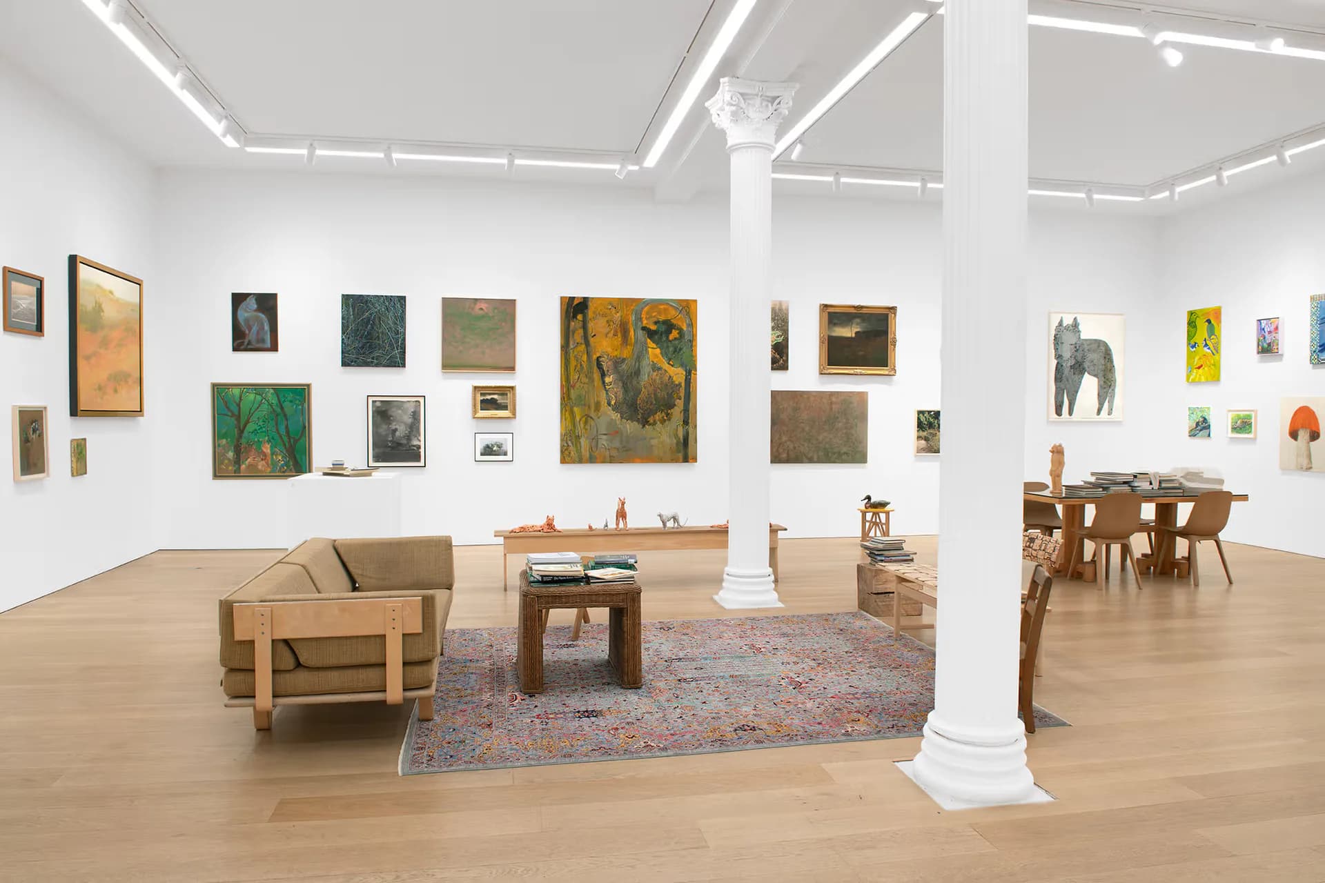 Canada Gallery's bright Tribeca interior with wooden furniture, white columns, and colorful paintings displayed on white walls.