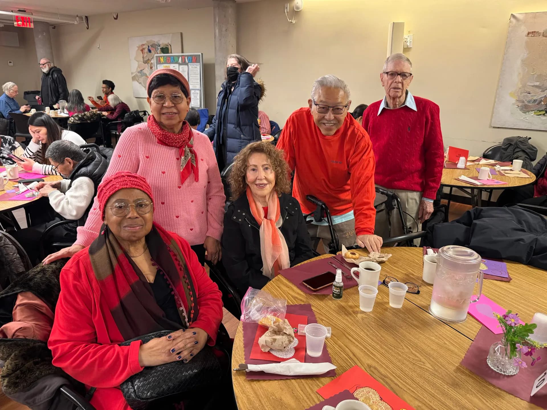 Group of people in red clothing gathered at tables in an indoor community space, Carter Burden Center for the Aging event.
