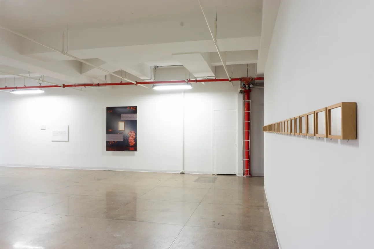 Gallery installation view with photograph artwork, wooden-framed series along right wall, polished concrete floor, fluorescent and red pipe elements.