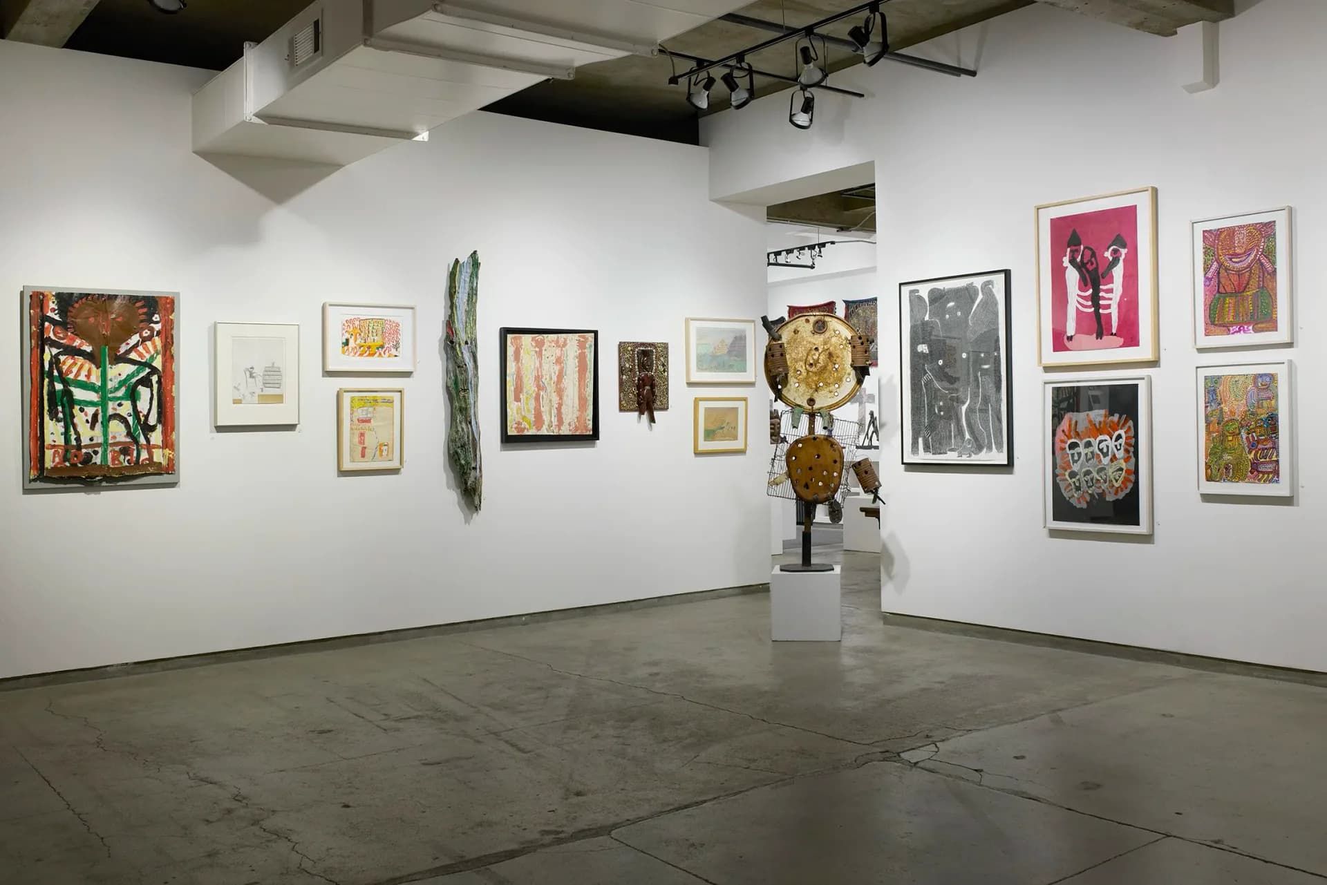 Gallery interior at Cavin-Morris Gallery showing white walls with varied framed artworks, sculptures, and three-dimensional pieces displayed across the space.