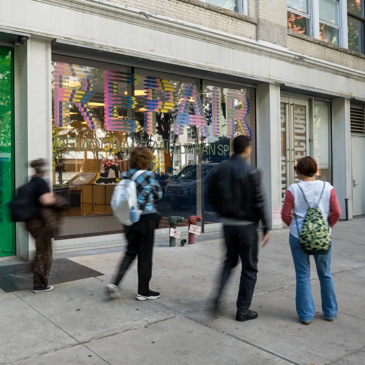 Storefront exterior of Center for Architecture with colorful window display and pedestrians walking past on urban street.