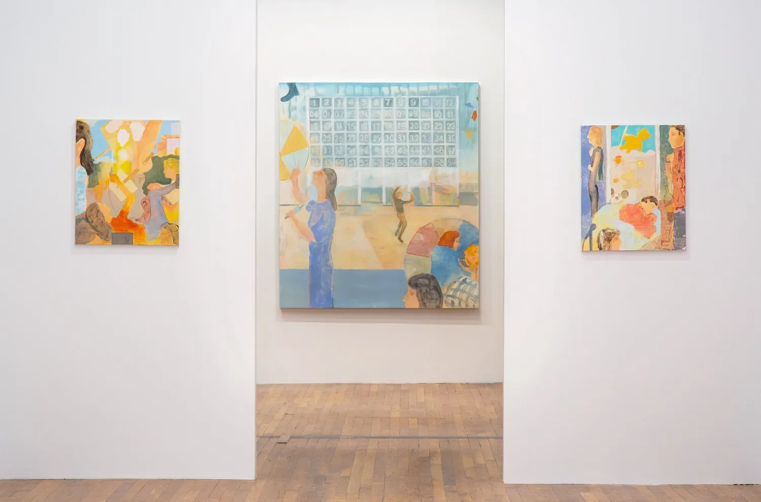 Gallery interior with three colorful abstract paintings on white walls and wooden floor.