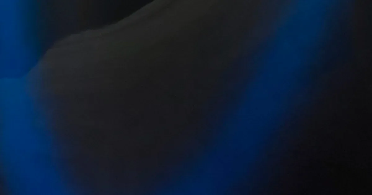 Dark abstract image with blue-toned background and indistinct shapes.