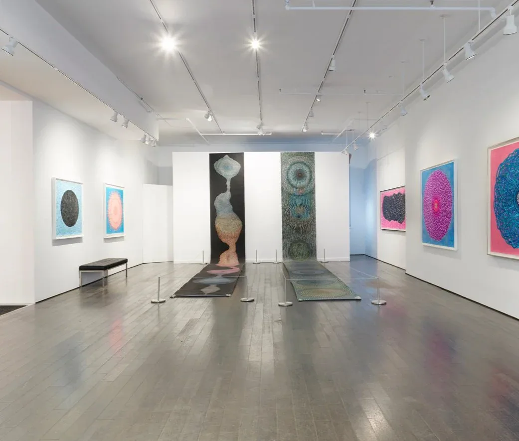 Chase Contemporary gallery interior with polished concrete floor, white walls, colorful abstract artworks on walls, and tall sculptural forms in center of space.