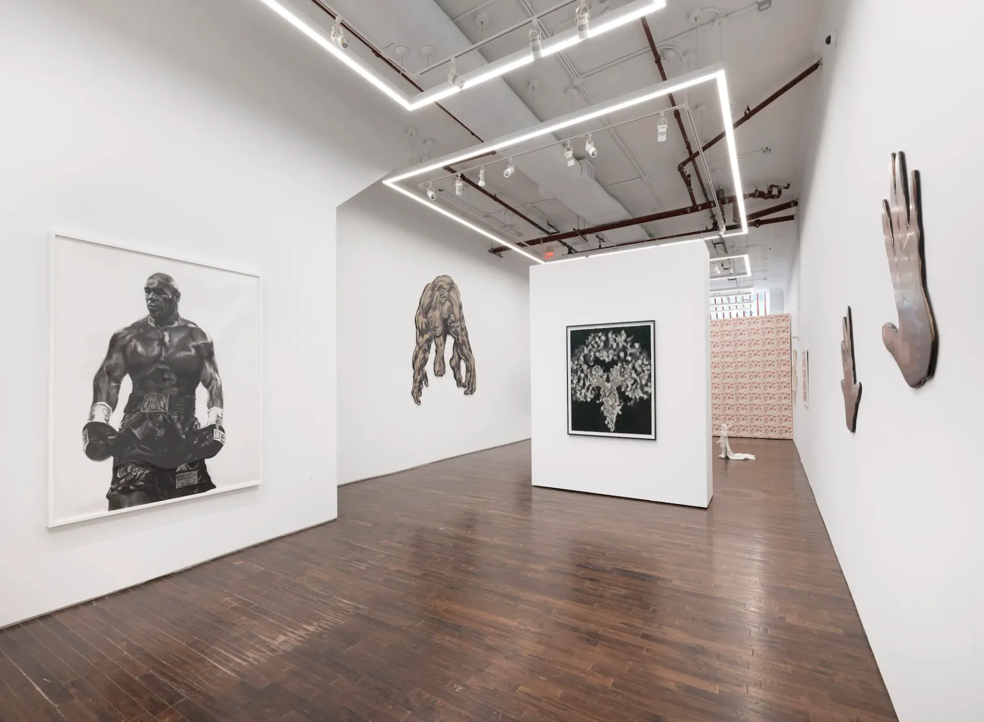 Cristin Tierney Gallery exhibition space with wood flooring, white walls displaying black and white artworks, including standing and hanging pieces, modern track lighting overhead.