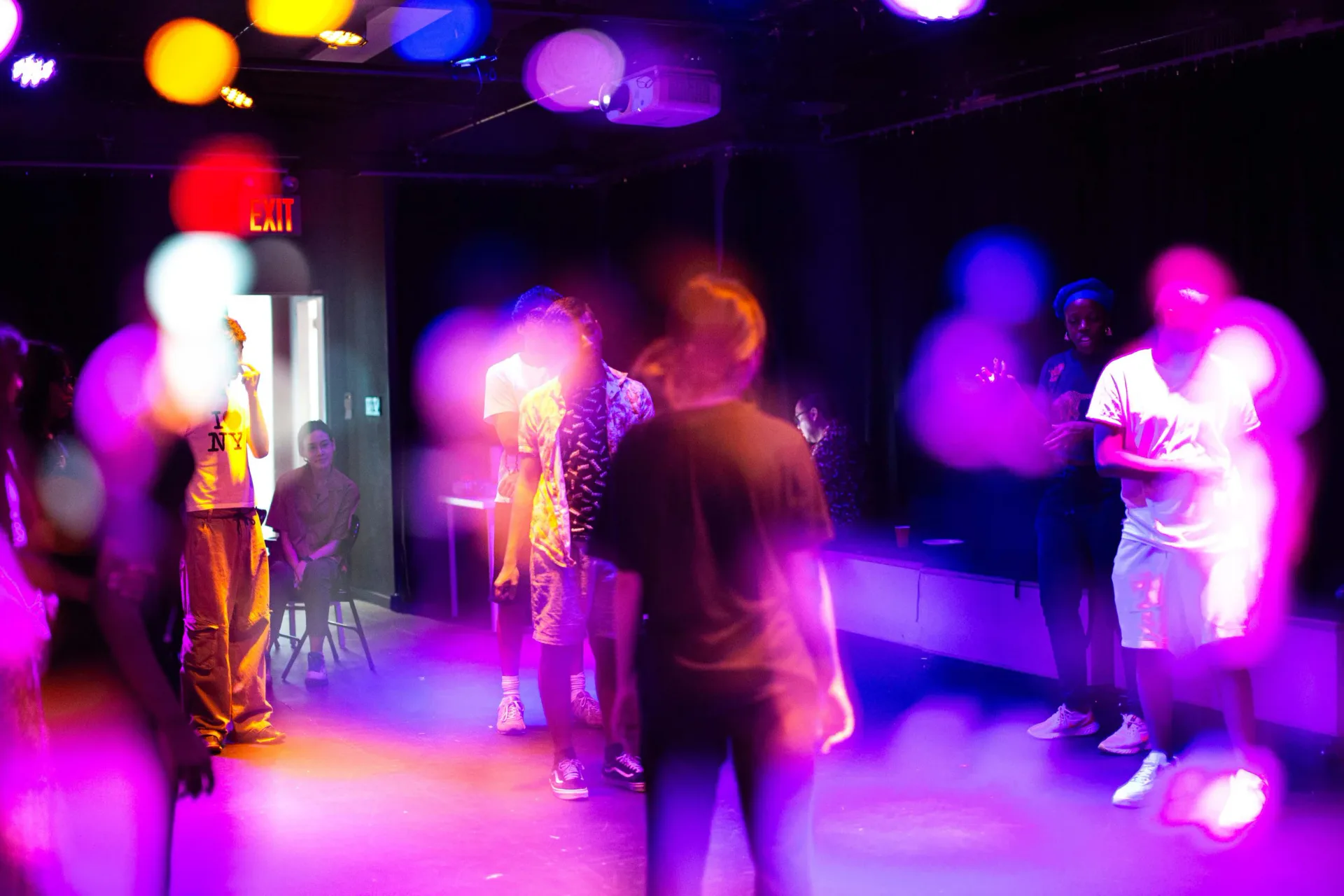 Interactive performance or installation at Culturehub with participants in a dark space illuminated by vibrant purple, pink, and yellow lighting.