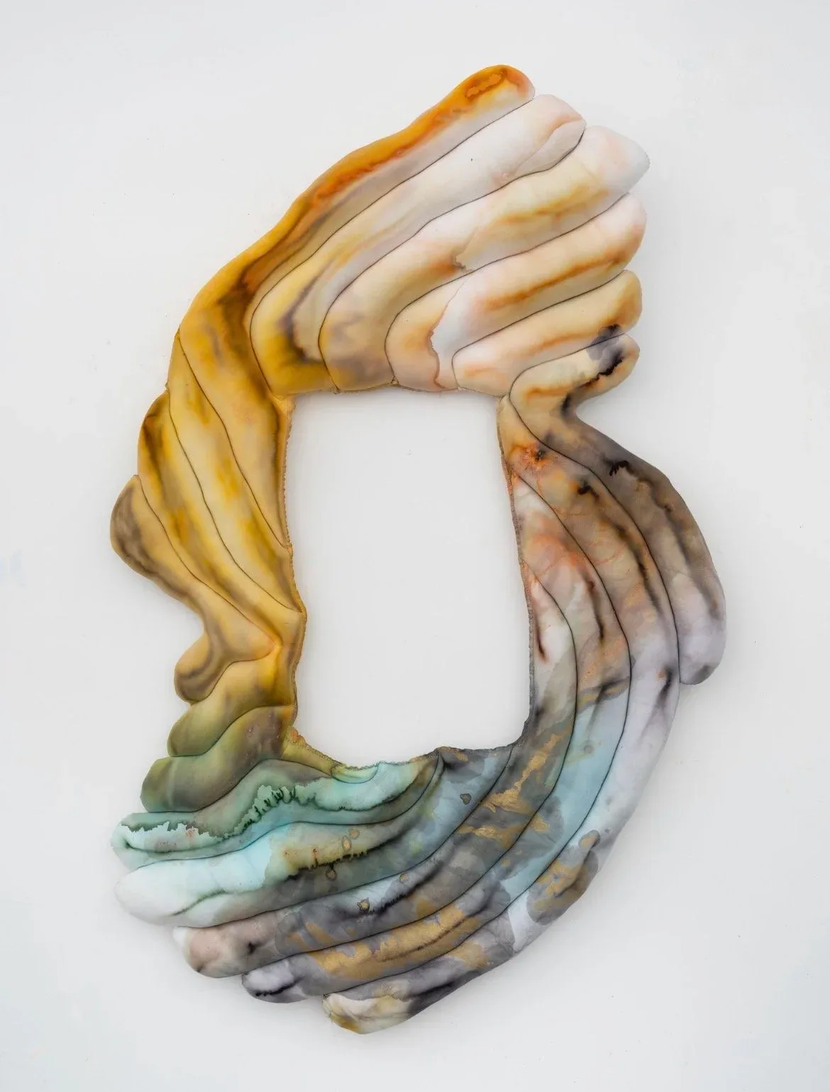 Abstract sculptural form made of layered fabric or textile in ochre, cream, gray, and teal tones, creating a hand-like curved shape with a hollow white center.