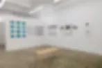 Interior of a white-walled gallery space with small framed artworks on the walls and a low platform, likely Deborah Bell Photographs in Chelsea