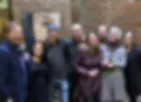 Blurred photograph of a group of people gathered indoors, details obscured.