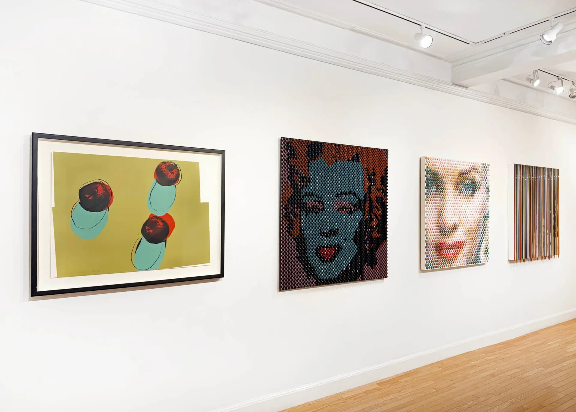 Gallery wall displaying four framed artworks: yellow abstract circles, dark teal portrait head, monochromatic face, and vertical striped pattern.