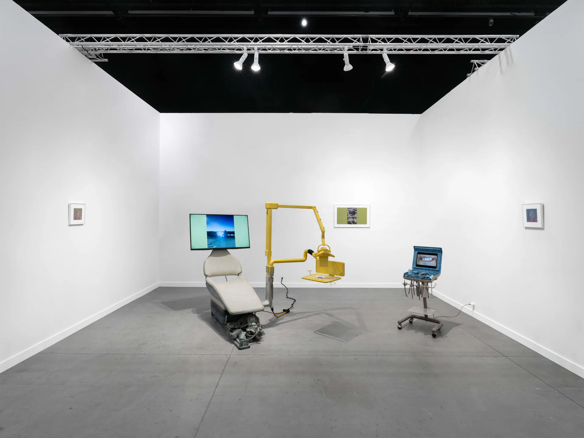 EUROPA gallery interior with white walls, gray concrete floor, and industrial black ceiling. Yellow robotic arm and multiple monitors display digital artworks.
