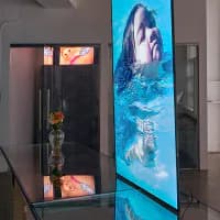 EUROPA gallery display featuring mixed-media installations: dark sculptural form and vertical digital screen showing abstract blue aquatic imagery.