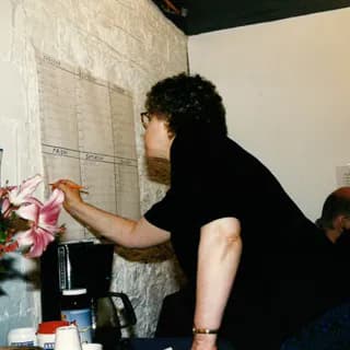Person in black shirt working on wall installation with flowers and materials visible at Fountain House Gallery studio.